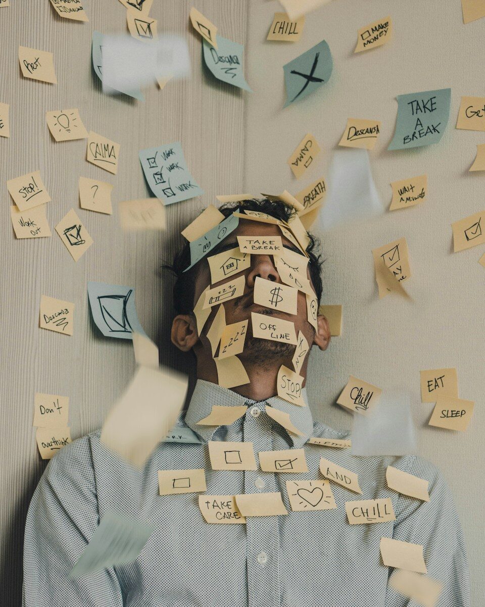 man covered in sticky notes at office desk